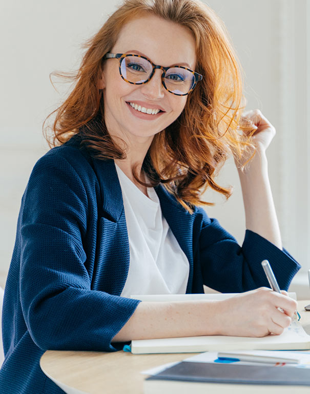 a woman in glasses is sitting at a table with a notebook