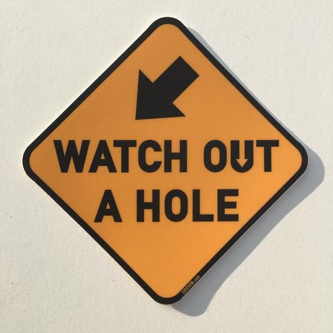 a sign that says watch out a hole