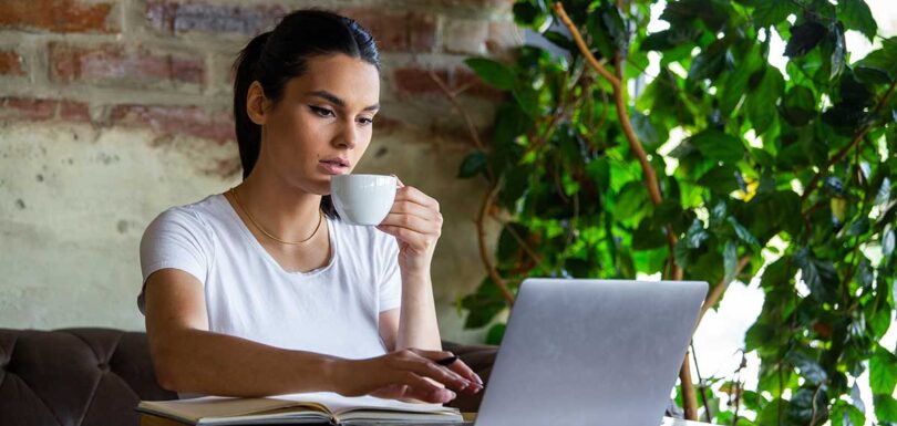 a woman sitting at a table with a laptop and a cup of coffee